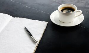 机の上に置かれたコーヒーとノート